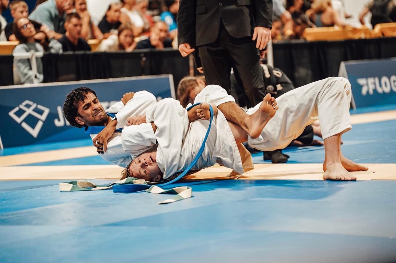 Two athletes grappling in the gi during a match