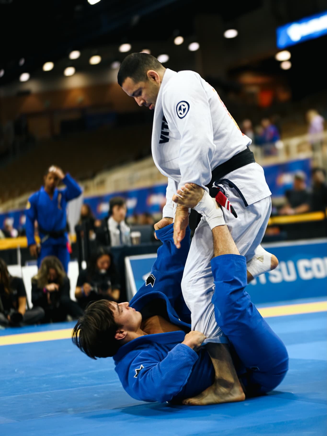 Black belt athlete standing over an opponent in a gi match